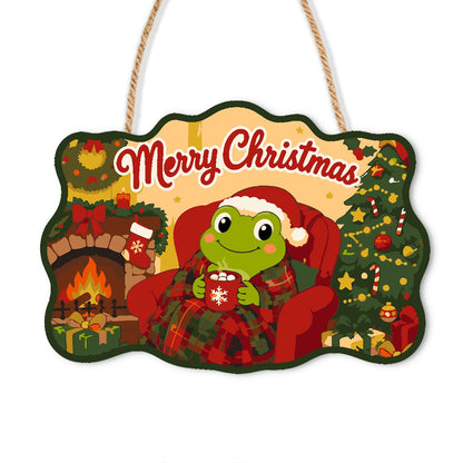 Fireside Frog with Cocoa paint by numbers hanging sign – Frog in a Santa hat holding a mug of cocoa in a red armchair by a fireplace and Christmas tree, on a wooden sign with a rope hanger