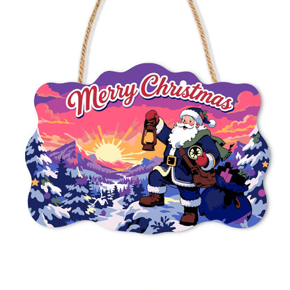 Lantern-Bearing Mountain Santa paint by numbers hanging sign – Santa with a walking stick holding up a lantern on a snowy mountain trail at sunset under a purple sky, on a wooden sign with a rope hanger