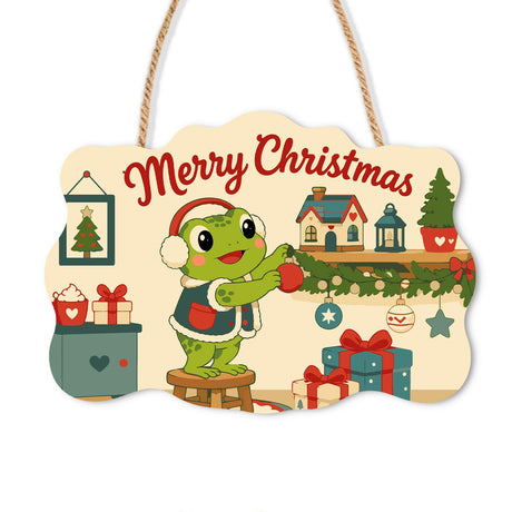 Frog Decking the Village Mantel paint by numbers hanging sign – Frog in a Santa hat standing on a stool placing ornaments on a garland mantel with tiny village houses, on a wooden sign with a rope hanger