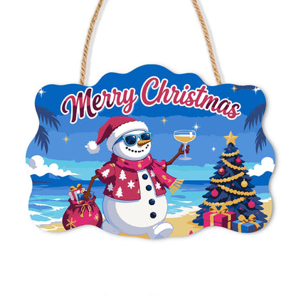 Pink Aloha Snowman by the Tree paint by numbers hanging sign – Snowman in a Santa hat and pink floral shirt raising a glass by a decorated tree on a beach under a deep blue sky, on a wooden sign with a rope hanger