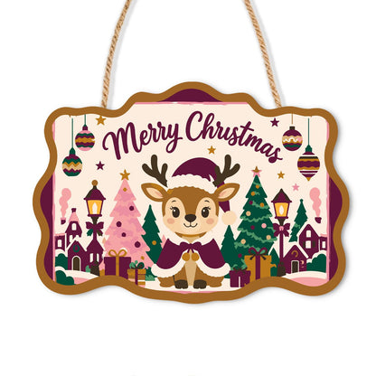 Plum Cloak Reindeer in Village paint by numbers hanging sign – Young reindeer in a plum Santa hat and cape in a lamplit village with pink and green Christmas trees, on a wooden sign with a rope hanger