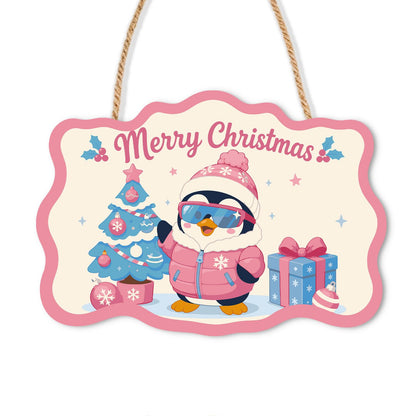 Pink Puffer Penguin Christmas paint by numbers hanging sign – Penguin in a pink beanie, ski goggles and pink puffer jacket beside a blue Christmas tree and gifts, on a wooden sign with a rope hanger