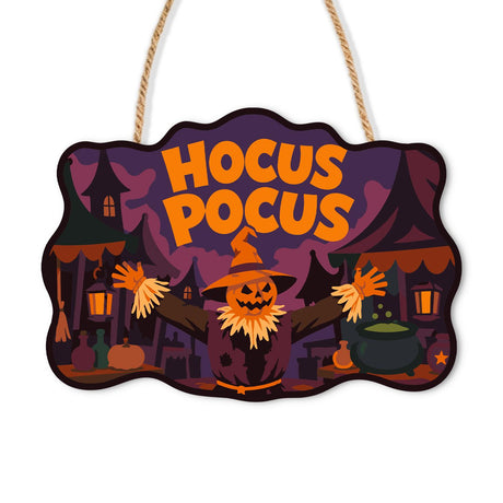 Spellbound Village Scarecrow paint by numbers hanging sign – Pumpkin-headed scarecrow with arms spread in a dusky witch village with a cauldron and lanterns, lettered Hocus Pocus, on a wooden sign with a rope hanger