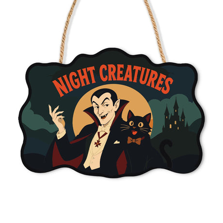 Vampire and Bow-Tie Cat paint by numbers hanging sign – Caped vampire beside a black cat in a bow tie before a moon and castle, Night Creatures lettering, on a wooden sign with a rope hanger