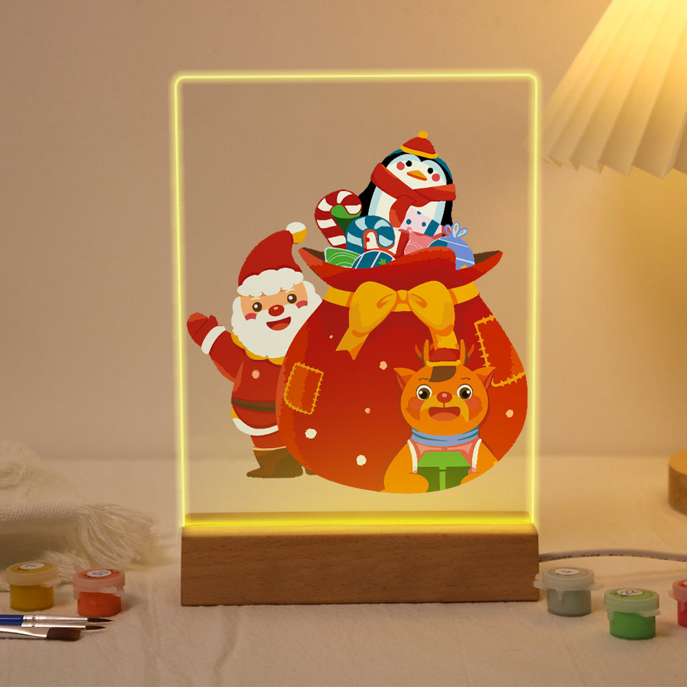 Giant Gift Sack with Penguin paint by numbers light-up sign – Waving Santa beside a giant red sack with a yellow bow, a penguin on top and a reindeer in front, lit up on its wooden base