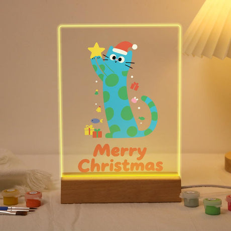 Polka-Dot Cat Reaching for a Star paint by numbers light-up sign – Tall blue cat with green spots in a Santa hat stretching up to touch a gold star, with small gifts and fish, lit up on its wooden base