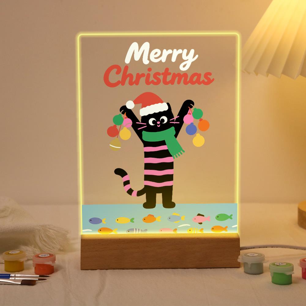 Santa-Hat Cat with Bauble Garland paint by numbers light-up sign – Black cat with pink stripes in a Santa hat and green scarf holding up a string of colorful baubles above a row of fish, lit up on its wooden base