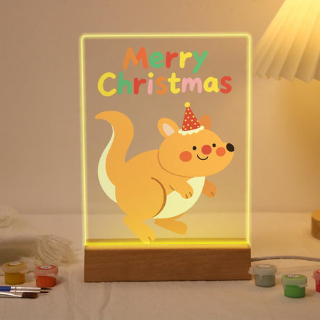 Hopping Holiday Kangaroo paint by numbers light-up sign – Smiling kangaroo in a red polka-dot party hat hopping below colorful Merry Christmas letters, lit up on its wooden base