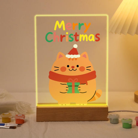Ginger Cat with a Green Gift paint by numbers light-up sign – Chubby orange cat in a Santa hat and red scarf hugging a green gift box below Merry Christmas letters, lit up on its wooden base