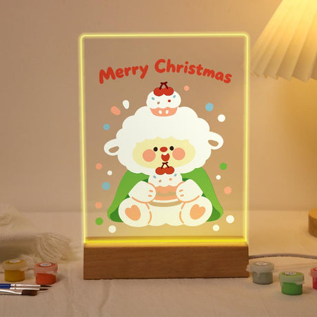 Little Lamb with a Cherry Cake paint by numbers light-up sign – Fluffy white sheep with a cupcake on its head holding a cherry cake in front of a green cape, lit up on its wooden base
