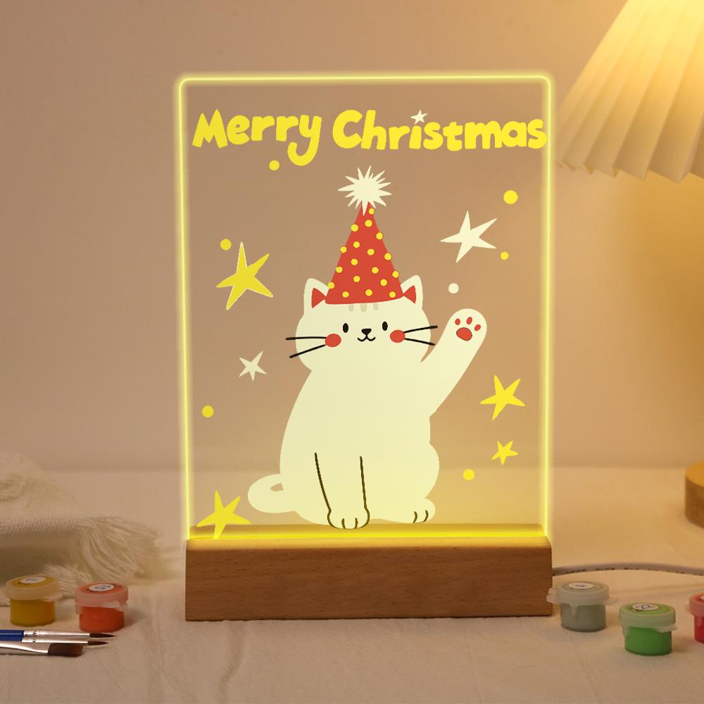 Waving Cat in a Party Hat paint by numbers light-up sign – White cat in a red polka-dot party hat waving a paw among yellow stars below Merry Christmas letters, lit up on its wooden base