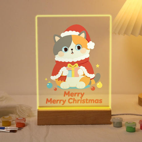 Calico Cat in a Santa Cape paint by numbers light-up sign – Calico cat in a red Santa hat and cape holding a small gift above Merry Merry Christmas lettering, lit up on its wooden base