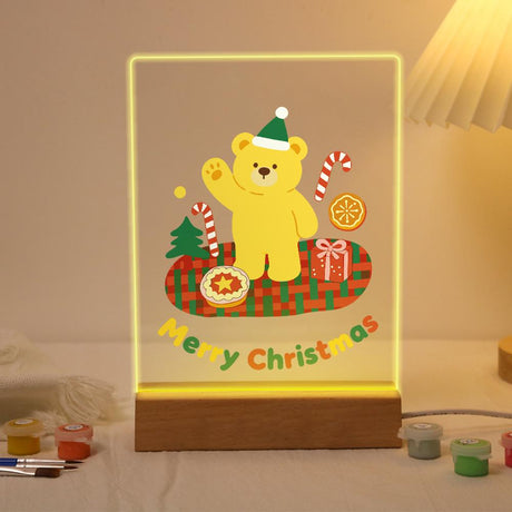 Elf Hat Bear's Holiday Picnic paint by numbers light-up sign – Yellow bear in a green elf hat waving on a red plaid blanket with a pie, a gift and candy canes, lit up on its wooden base
