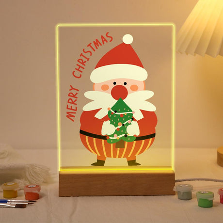Santa Hugging a Tiny Tree paint by numbers light-up sign – Rosy-nosed Santa holding a little decorated Christmas tree below arched Merry Christmas lettering, lit up on its wooden base