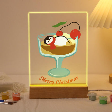 Penguin Napping in a Sundae Glass paint by numbers light-up sign – Penguin lying in a sundae glass of pudding topped with red cherries above Merry Christmas script, lit up on its wooden base