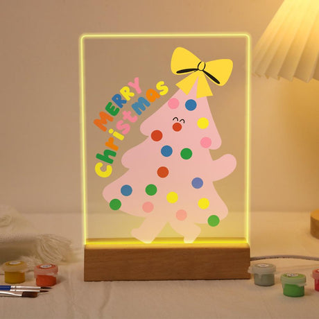 Happy-Faced Pink Christmas Tree paint by numbers light-up sign – Smiling pink Christmas tree with colorful polka dots and a yellow bow beside rainbow Merry Christmas, lit up on its wooden base