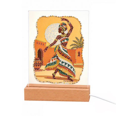 Dancer in a Bold Patterned Gown light-up pearl painting – Woman in a headwrap and bold patterned dress dancing before a golden full moon and earthen adobe walls