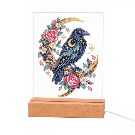 Raven on a Rose Crescent Moon light-up pearl painting – Black raven dotted with gold stars perched on a crescent moon wreathed in pink roses