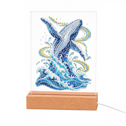 Humpback Breaching in Gold Swirls light-up pearl painting – Blue humpback whale leaping upward from foaming waves with golden swirls of spray