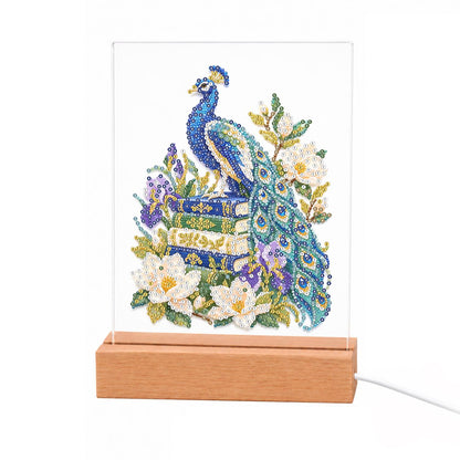 Peacock Perched on Old Books light-up pearl painting – Blue peacock perched on a stack of books, its long tail draping among white magnolias and purple irises