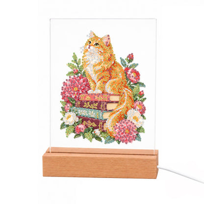 Fluffy Ginger Cat in Peonies light-up pearl painting – Fluffy ginger cat sitting on a stack of books surrounded by pink and red flowers