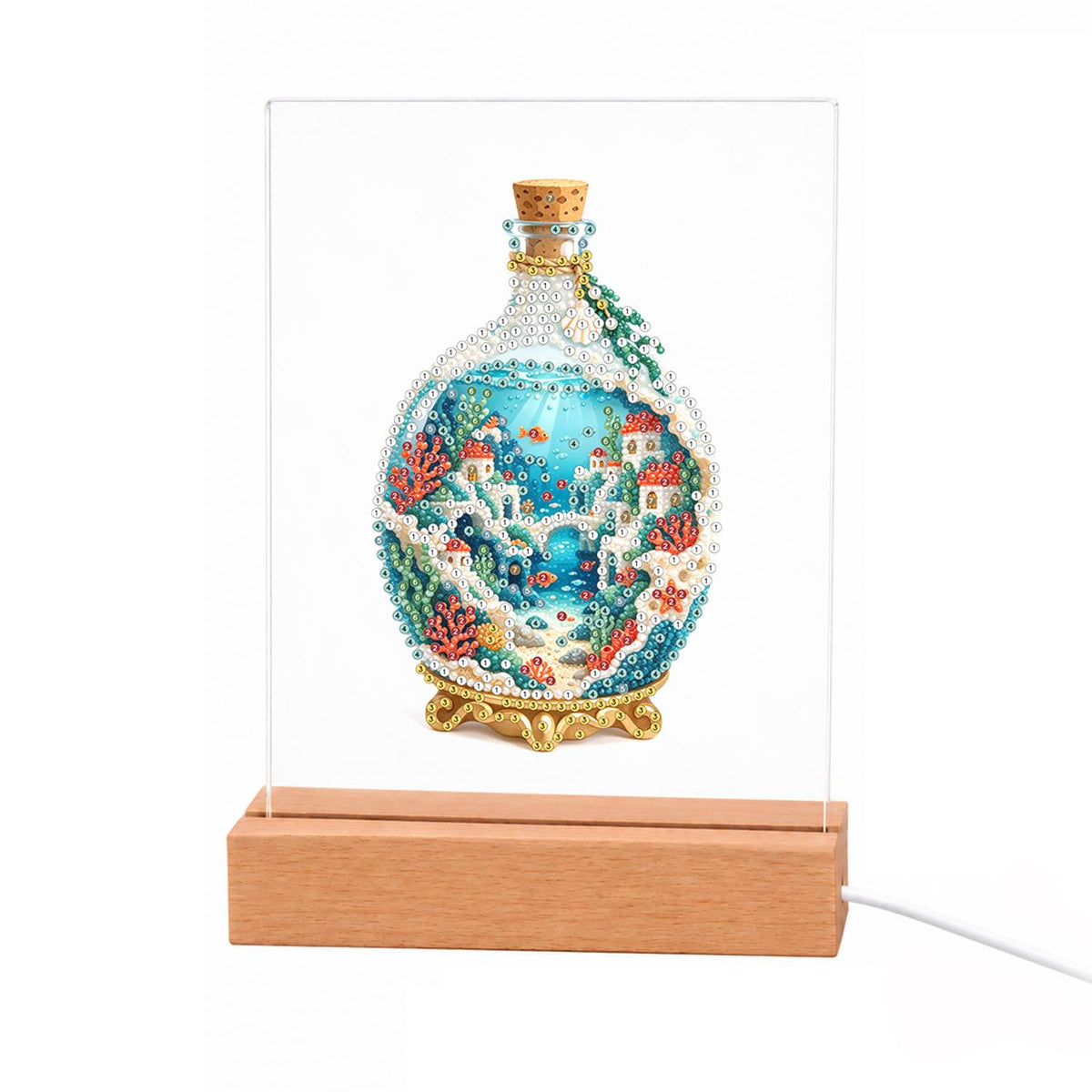 Seaside Village in a Corked Bottle light-up pearl painting – Round corked glass bottle on a gold stand holding white cliffside houses, blue sea and coral