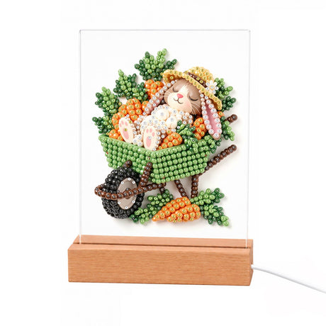 Sleepy Bunny in a Carrot Cart light-up pearl painting – Bunny in a straw hat napping in a green wheelbarrow full of carrots and leafy greens