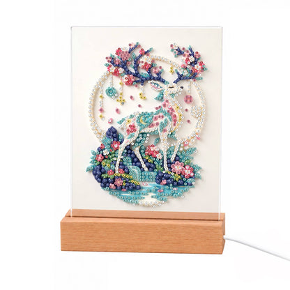Blossom-Antlered Deer by the Moon light-up pearl painting – White ornate deer with pink and blue blossom antlers on a flowery island before a pale moon ring