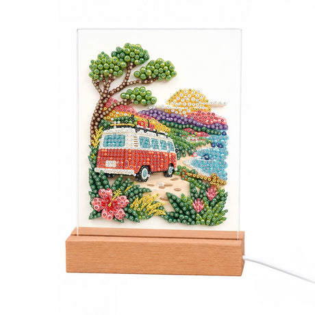 Vintage Camper on a Coastal Road light-up pearl painting – Red-and-white vintage camper van on a coastal road under a leafy tree, with sea, sunset and flowers