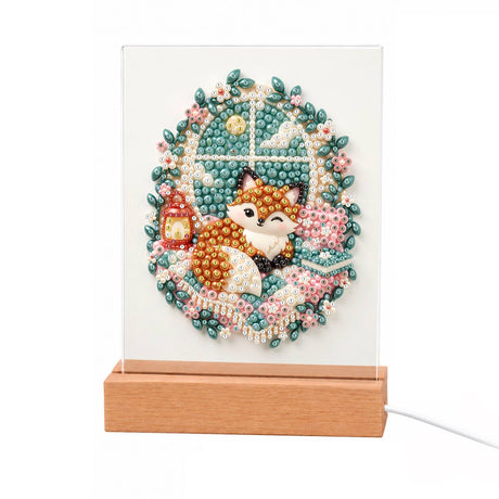 Cozy Fox by a Lantern Window light-up pearl painting – Fox curled up by a frosty window with a red lantern, framed by an oval wreath of pink flowers and leaves