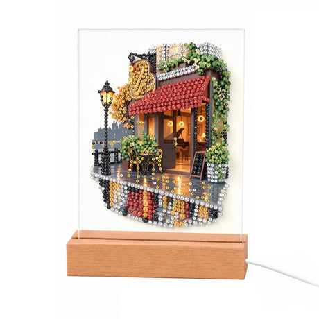 Lamplit Café with a Red Awning light-up pearl painting – Café with a red awning, glowing windows, potted plants and a street lamp on a wet reflective street