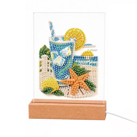 Iced Lemonade with a Starfish light-up pearl painting – Iced lemonade with a straw and lemon slices, an orange starfish and a white beach fence by the sea