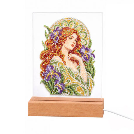 Auburn Muse Among Purple Irises light-up pearl painting – Woman with long flowing red curls in a green gown surrounded by purple irises under a golden arch