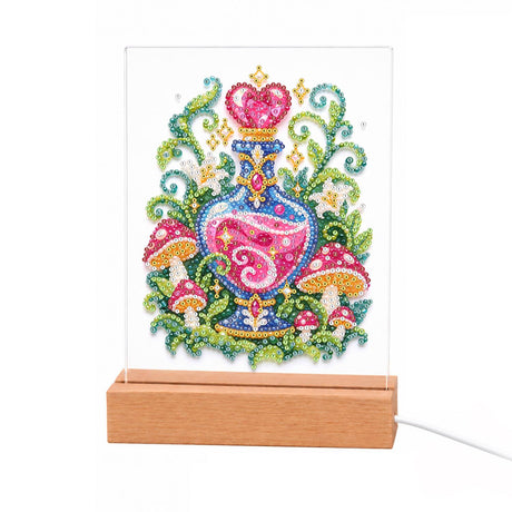 Love Potion Among Toadstools light-up pearl painting – Pink potion bottle with a heart-shaped stopper amid curling green leaves, flowers and red-capped mushrooms