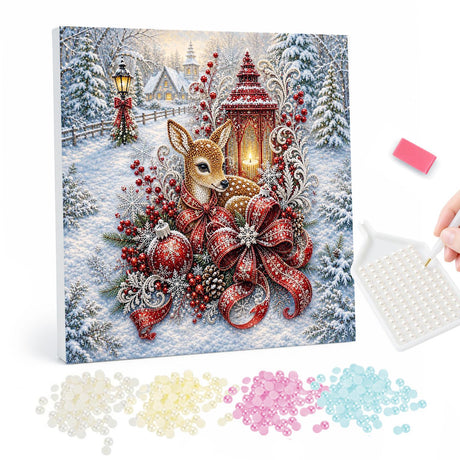 Fawn Beside a Red Lantern pearl painting – Fawn lying beside a red lantern and a large red ribbon bow with baubles in a snowy village scene