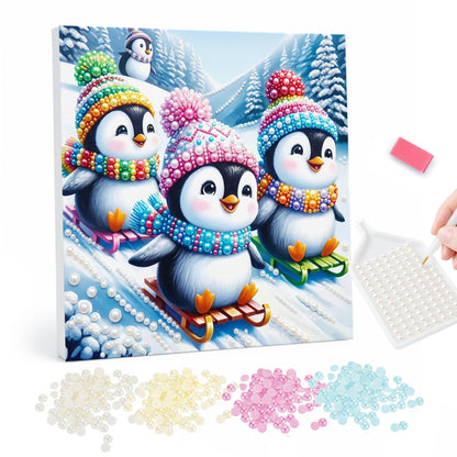 Three Penguins on Sleds pearl painting – Three penguins in colorful knit hats and scarves sledding down a snowy hill