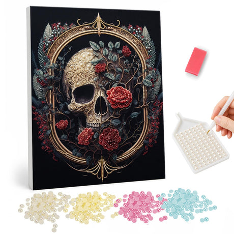 Skull in a Gilded Rose Frame pearl painting – Cream skull wreathed in red roses and dark leaves inside an ornate gold oval frame on black