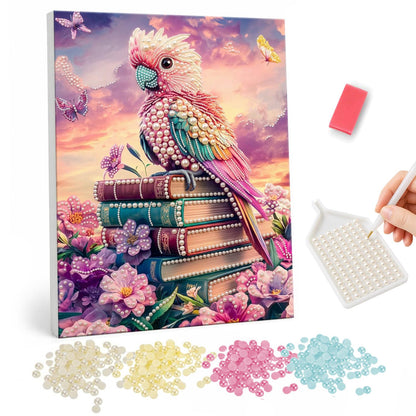 Sunset Cockatoo on a Book Stack pearl painting – Pink and peach cockatoo perched on a stack of old books among pink flowers under a sunset sky