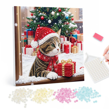 Tabby Cat by the Christmas Window pearl painting – Tabby cat in a Santa hat and red scarf leaning on a snowy windowsill beside a gift, tree behind
