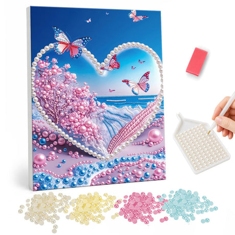 Cherry Tree Heart Over the Ocean pearl painting – Heart-shaped frame of beads around pink blossom trees and the sea, with pink butterflies in a blue sky