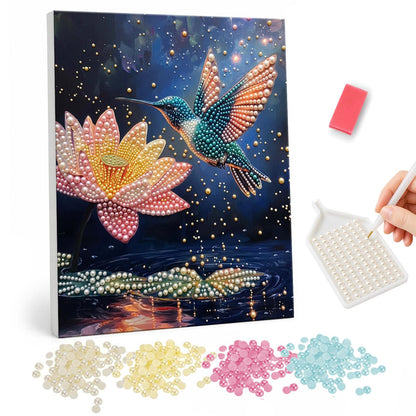 Night Pond Hummingbird pearl painting – Hummingbird with spread wings hovering beside a pink lotus above a dark pond with sparkles and lily pads