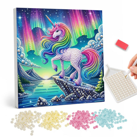Unicorn Under the Northern Lights pearl painting – White unicorn with a rainbow mane posing on a rocky ledge above a lake under glowing northern lights