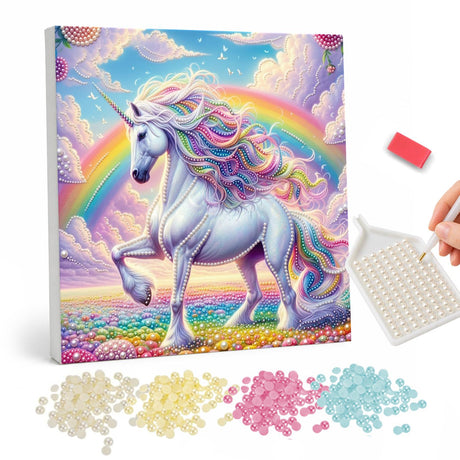Unicorn Beneath the Rainbow pearl painting – White unicorn with a pastel rainbow mane walking through a flower meadow under a rainbow and pink clouds