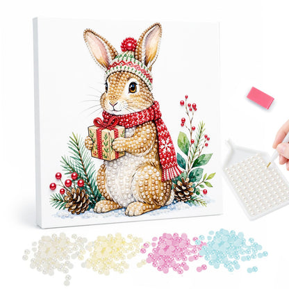 Bunny with a Wrapped Gift pearl painting – Brown rabbit in a knit pom-pom hat and red scarf holding a small gift among pine, berries and cones