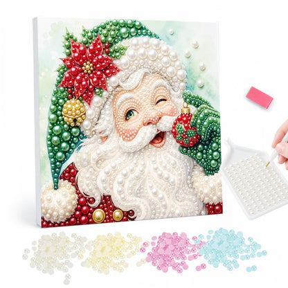Winking Santa in a Green Hat pearl painting – Winking Santa in a green hat with a red poinsettia, holding a small ornament