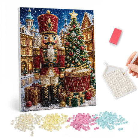 Nutcracker Drummer by the Tree pearl painting – Nutcracker soldier in red beside a drum, gifts and a lit Christmas tree in a snowy town square
