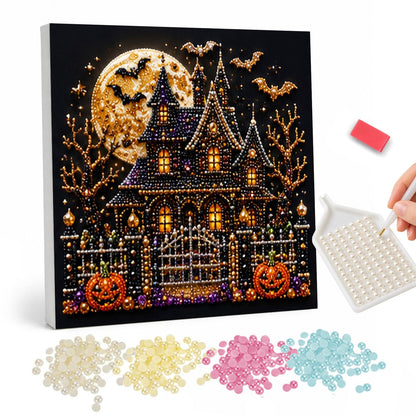 Gated Manor Beneath a Gold Moon pearl painting – Spired haunted house with glowing windows and an iron gate under a golden full moon with bats and pumpkins