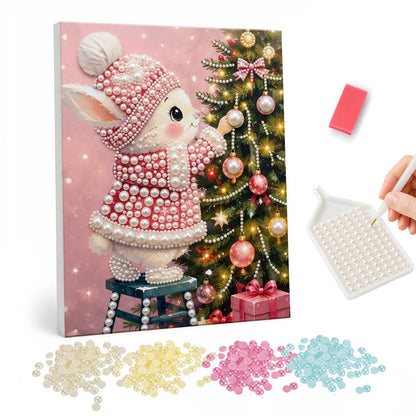 Bunny Trimming the Tree in Pink pearl painting – White bunny in a pink knit hat and coat standing on a stool to hang baubles on a Christmas tree