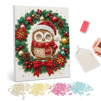 Santa-Hat Owl in the Wreath pearl painting – Round owl in a Santa hat and red scarf framed by a bauble and pinecone wreath with a red bow