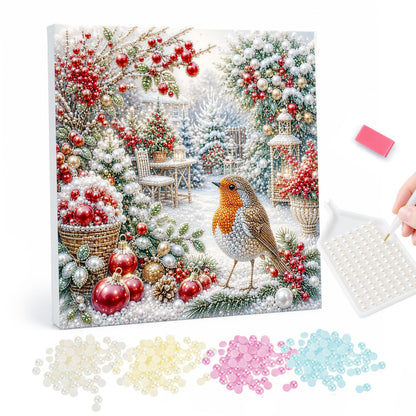 Robin Among Red Baubles pearl painting – Robin on snowy ground among red baubles, berries and frosted greenery in a white winter garden